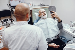 patient with dental implants seeing his new smile in a mirror 