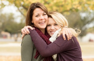 A mother and daughter hugging outside.