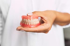 dentist holding set of full dentures