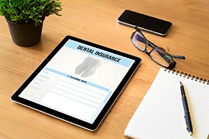 Dental insurance form on tablet next to notepad