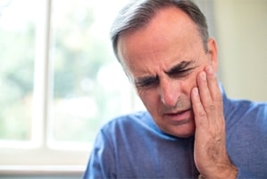 Man with toothache in Gainesville holding his cheek