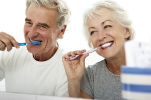 man and woman brushing their teeth