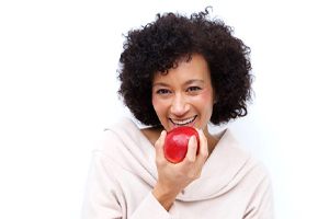 woman biting into a red apple