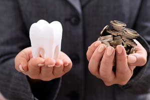 Hands holding tooth and money.