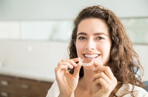 woman smiling holding Invisalign