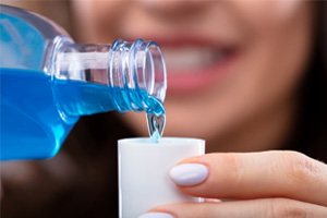 woman pouring mouthwash into cap  