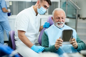 mature man looking in mirror in dental chair  