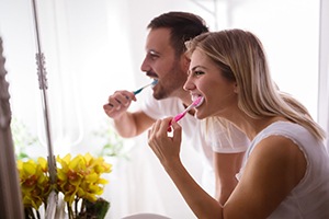 Younger couple brushing teeth together