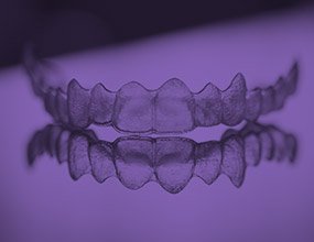 Invisalign tray on tabletop highlighted purple