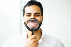 man holding magnifying glass in front of his smile