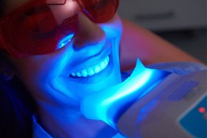 : woman getting teeth whitening in dental office