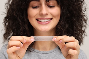 Woman using a teeth whitening strip