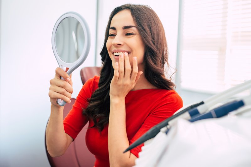 Woman looking at her dental implant in the mirror